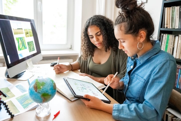 Two young women preparing together concepts for climate protection on desk indoors