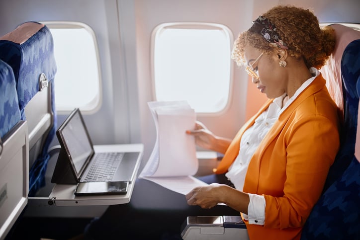 A businessperson works on their laptop while traveling on an airplane