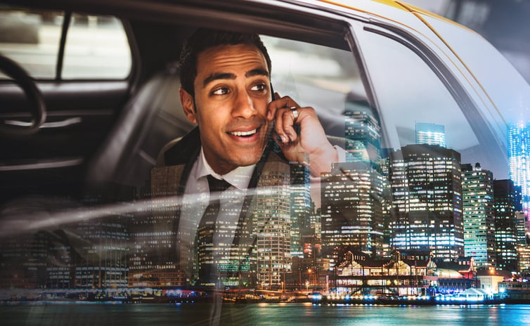 A businessperson talks on the phone in the back of a cab.